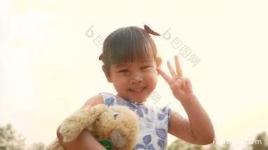 可爱<strong>的</strong>亚洲小女孩抱着泰迪熊在公园里感受爱情.
