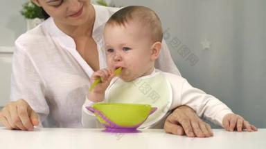 母亲看着他的宝宝用勺子吃饭
