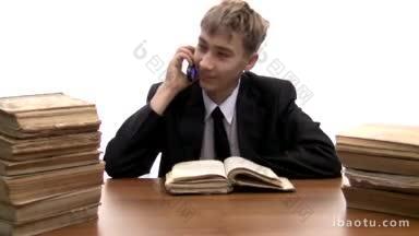 桌子后面拿着书的男孩在打电话