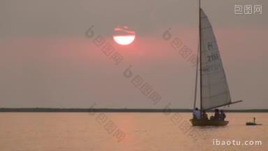 太阳球落在帆船后面的地平线上