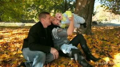 秋天的公园里，幸福的一家人抱着孩子