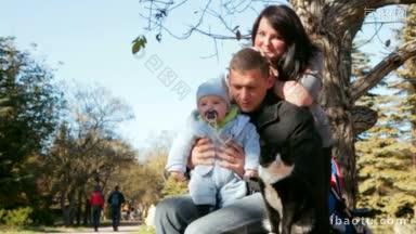 一家人带着蹒跚学步的孩子在秋天公园的长椅上看猫