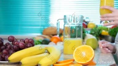 女服务员手里拿着一杯橙汁，在厨房附近放着很多蔬菜和水果