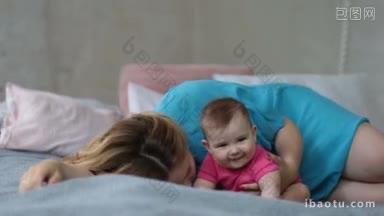 深情的年轻母亲<strong>亲吻</strong>她的幼女，而躺在床上的早上快乐的美丽妈妈<strong>亲吻</strong>和拥抱