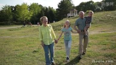 快乐的多代<strong>家庭</strong>手牵着手，在公园的草地上跳舞跳跃，积极的祖父母和孙辈享受