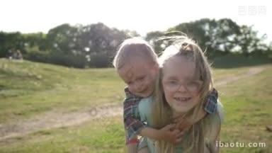 兴奋的姐姐给快乐的蹒跚学步的弟弟骑在公园草坪上阳光灿烂的一<strong>天</strong>可爱的年轻女孩带着她的小