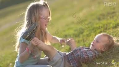 两个顽皮的孩子在<strong>公园</strong>的<strong>绿地</strong>上玩耍的侧视图，可爱的金发妹妹戴着眼镜亲吻肚子