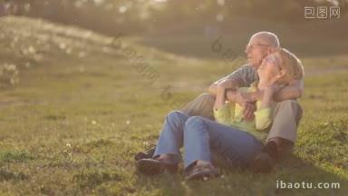 笑容满面的老夫妇坐在公园的草地上，回忆着他们幸福家庭生活的有趣时刻
