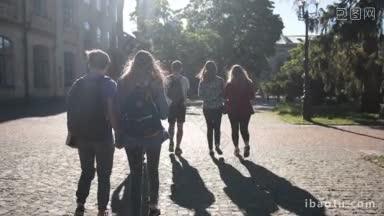 快乐的大学生在去大学的路上穿过公园的背影，一群年轻的大学<strong>朋友</strong>