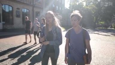 美丽的学生情侣走在大学校园里拿着书聊天