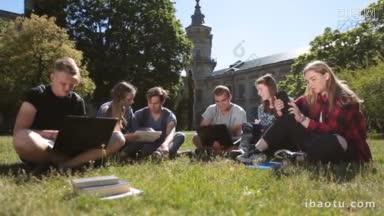 一群<strong>大学生</strong>坐在绿色的草地上，用笔记本电脑和数字平板电脑在大学校园工作