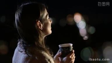 侧面可爱的年轻长棕色头发的女士享受夜晚城市的灯光，同时喝热的<strong>新鲜</strong>咖啡从<strong>外卖</strong>
