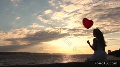 美丽的长金发<strong>女孩</strong>手拿氦气红色心形气球坐在海堤上观看