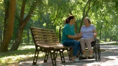 在夏季公园户外，护工与轮椅上的残疾老年妇女交谈