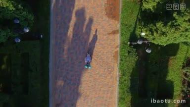 空中拍摄的公园里，护工带着轮椅上的残疾老人在户外散步的镜头