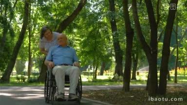 在夏季公园外，一名老年妇女推着轮椅上的丈夫全高清慢动作镜头