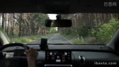 自信的<strong>女</strong>司机开车穿过森林在两车道的乡村道路在夏天的一天内的景色