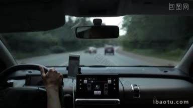 一名女子在繁忙的<strong>高速公路</strong>上开车，从车辆内部看，模糊的绿色森林和背景交通