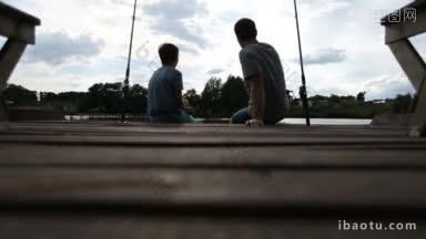 悠闲的父亲和十几岁的儿子坐在木制码头上，在<strong>平静</strong>的海面上钓鱼，彼此联系和交流