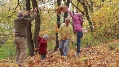 <strong>快乐</strong>的爷爷奶奶和可爱的孙子孙女在<strong>秋天</strong>的公园里扔黄叶无忧无虑的老夫妇和微笑着玩树叶的兄弟姐妹