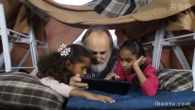 可爱<strong>的</strong>两个混血姐姐向白人祖父展示如何使用电子平板电脑，而躺在小<strong>房间的椅子</strong>