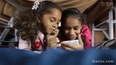 两个<strong>微</strong>笑的非裔美<strong>国学</strong>前班女孩在智能手机上浏览网页，兴奋的小妹妹沉浸在在线游戏中