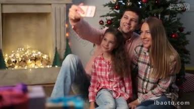在平安夜的时候，家庭自拍可爱的微笑的家庭坐在圣诞树的地板上，拍自己