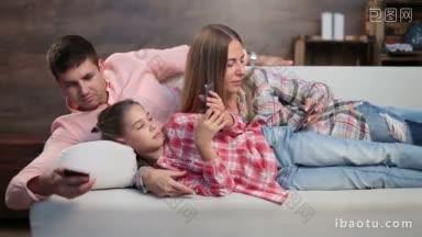 现代家庭看重有吸引力的家庭和<strong>可爱</strong>的女儿一起躺在沙发上用智能手机上网