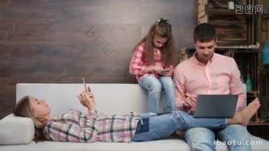 轻松的家庭与孩子一起使用手机和笔记本电脑，<strong>同时</strong>在现代的家庭室内帅气的父亲使用一起休闲