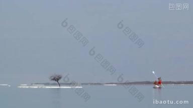 游客在导游的带领下乘坐桨板在死海观赏白色的咸咸的小岛