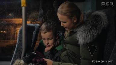 母亲和孩子在冬天晚上乘公共汽车旅行时用<strong>手机</strong>打发时间，他们在车上看电影或动画片