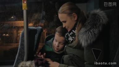 年轻的母亲和儿子在冬末的傍晚乘坐公共汽车旅行，他们玩智能<strong>手机</strong>打发时间
