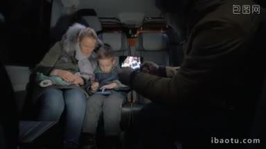 父母和<strong>孩子</strong>乘坐小巴旅行，男子拍摄了母子用智能手机<strong>玩游戏</strong>的手机视频