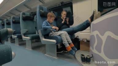 母亲和儿子在深夜乘坐特快列车旅行，母亲用<strong>手机</strong>充电，孩子用平板电脑娱乐