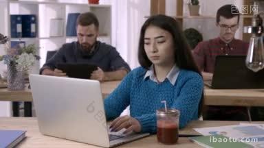迷人的亚洲女孩工作与文件和笔记本电脑在<strong>开放</strong>空间的办公室与同事使用数字设备的背景年轻