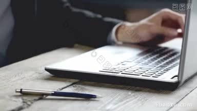 一名男子在一张质朴的木桌上用笔记本电脑工作，双手靠近