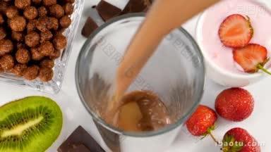 <strong>巧克力</strong>和牛奶在杯子里流动的早餐慢动作健康的早餐吃水果