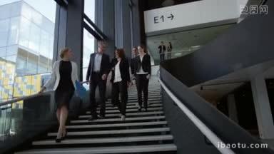 现代商务人士走在写字楼玻璃大厅的楼梯上