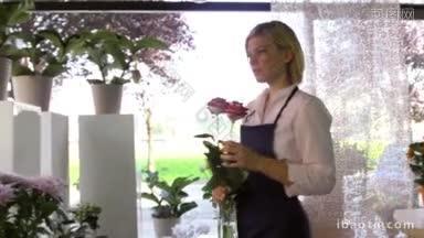 年轻迷人的女子工作在花店准备花束和闻<strong>红玫瑰</strong>