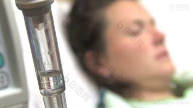 一个静脉滴注室的特写，背景是一个<strong>生病</strong>的女人躺在医院的床上