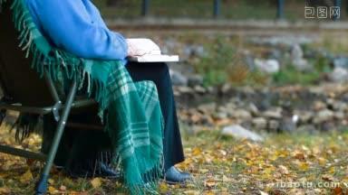 一位老妇人在<strong>河边</strong>的秋天<strong>公园</strong>看书，享受退休生活