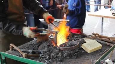 铁匠从火中取出两个热的金属环，小男孩吹大锤子将它们连接起来