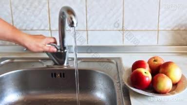 女人用冷水打开水龙头，把漂亮的苹果彻底洗<strong>干净</strong>，然后放进盘子里