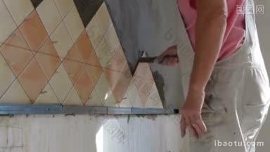 一名男子用抹刀在厨房墙上涂瓷砖