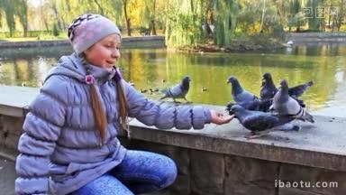 可爱的少女站在秋天的城市公园里，用手喂爆米花<strong>鸽子</strong>，靠近湖的特写