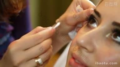 化妆师正在用刷子给一位美丽的年轻女子的眼睑化妆
