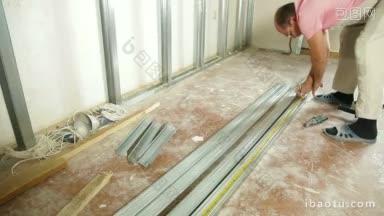 在房子里安装石膏板墙的人正在计量一种大小的石膏板钉
