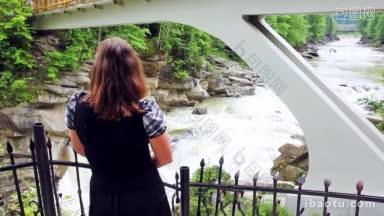一位漂亮的女士站在观景台上，看着桥下的雅雷姆察瀑布