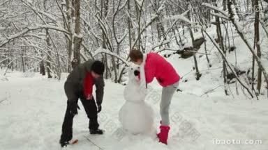 一对十几岁的情侣在冬天的雪林里堆雪人