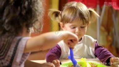快乐的孩子们在午餐时玩得很开心，一个<strong>女孩</strong>在学校帮助她的朋友吃意大利面